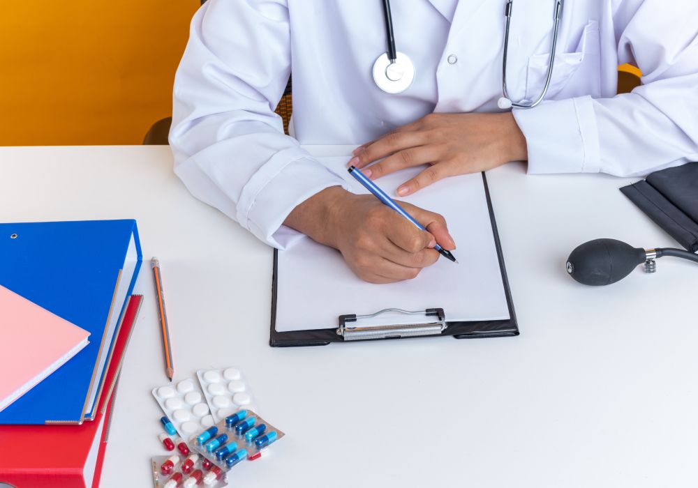 Aminophylline Doctor sitting at a desk, pen in hand, prescribing a medical pad.