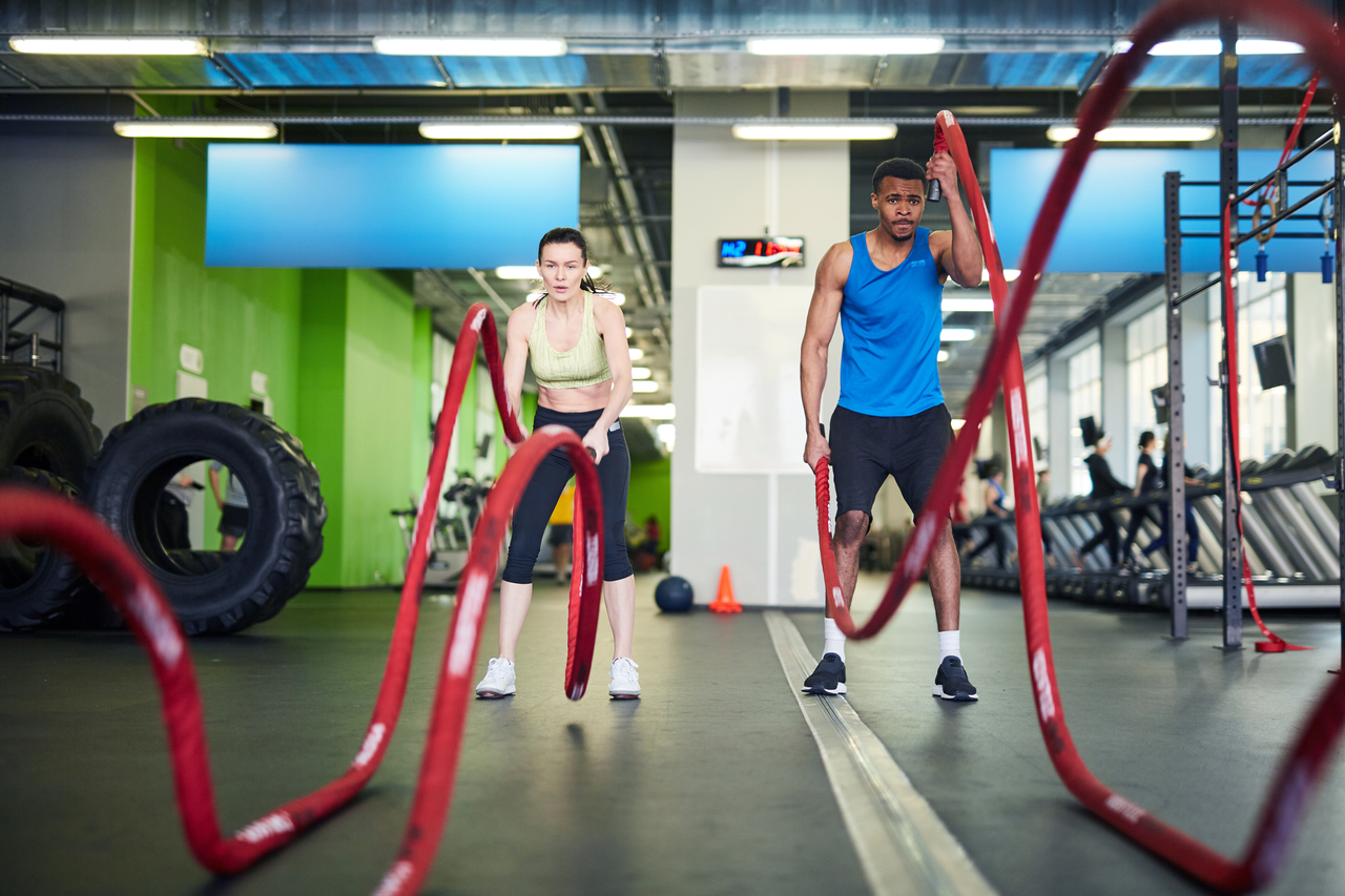 A man and woman working out with heavy ropes after taking Caffeine Anhydrous