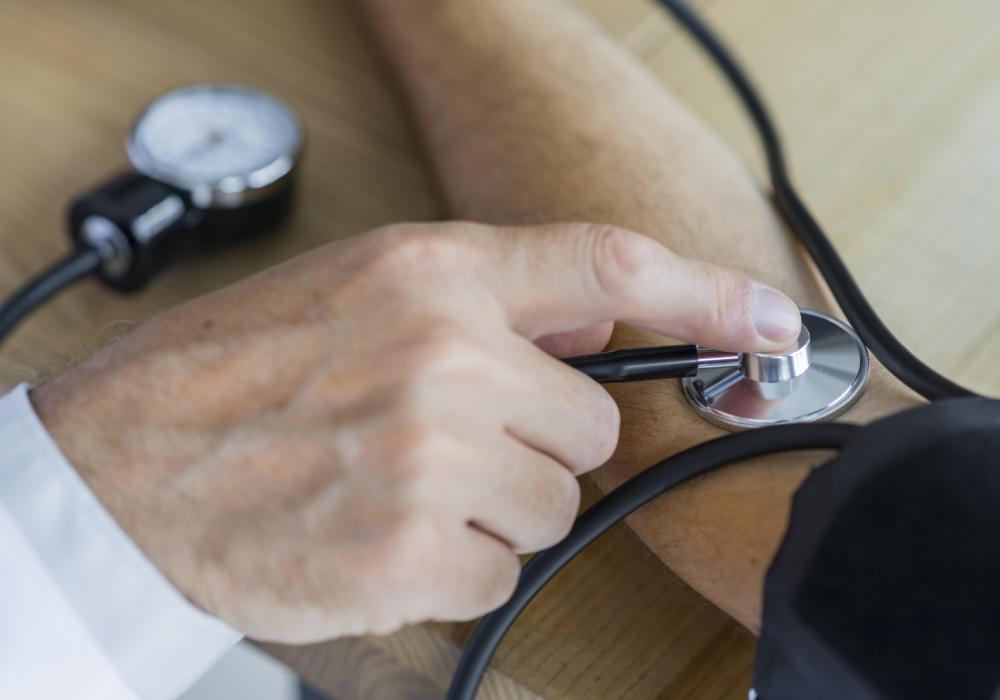 A woman sitting in a chair while a healthcare professional measures her blood pressure using a sphygmomanometer. 