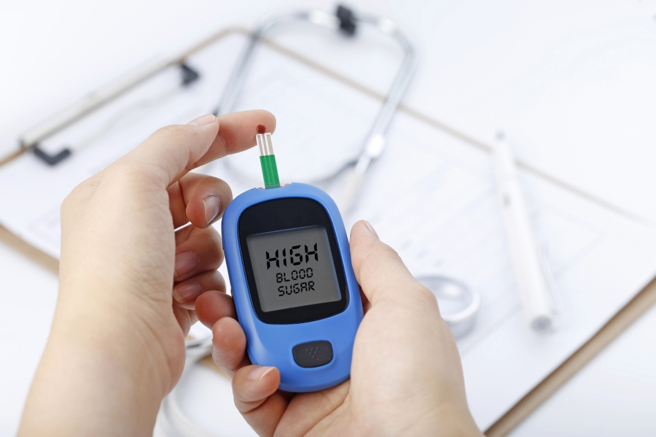 A close-up image of a woman checking her glucose levels with a blood sugar monitor indicating a normal result.