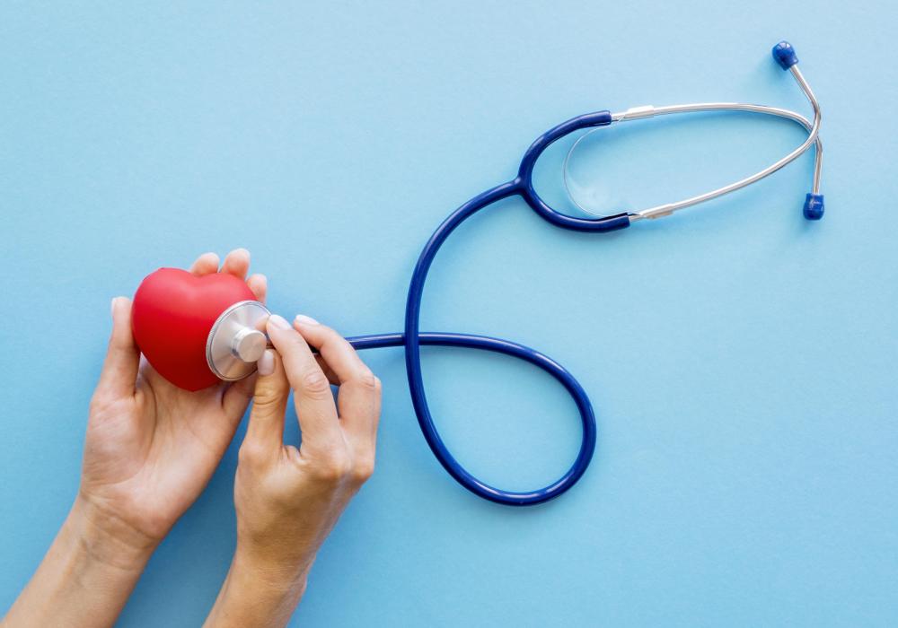 A medical professional in a white coat using a stethoscope to listen to a heart.