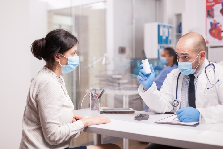 Patient wearing a face mask undergoing a medical check-up with a doctor in a clinic, demonstrating responsible health measures during the appointment.